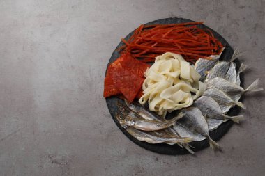 Gri masada birçok farklı kurutulmuş balık aperatifleri, üst manzara. Metin için boşluk