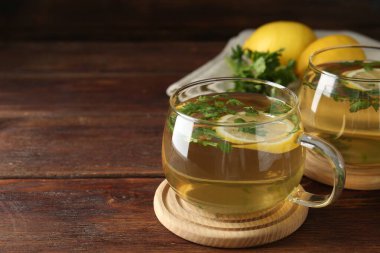 Tahta masada limon dilimleri olan sağlıklı maydanoz çayı, yakın plan ve mesaj için yer. Detoks içeceği