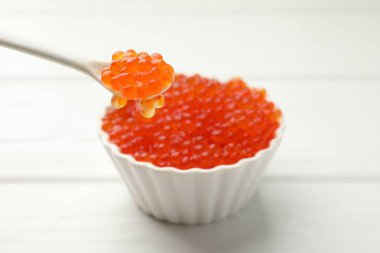 Lezzetli kırmızı havyarı beyaz ahşap masada kaşıktan kaşığa alıp yakın plan çekiyoruz.