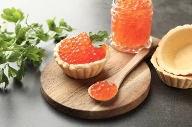 Kırmızı havyar, kaşık ve maydanozlu kanepe gri masada, yakın plan.