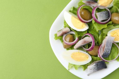 Ringa balıklı lezzetli salata, yeşil arka planda yumurta ve sebzeler, üst manzara. Metin için boşluk