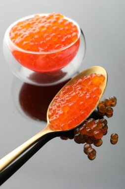 Gri ayna yüzeyinde kırmızı havyar, yakın plan.