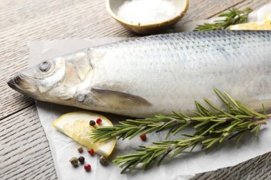 Ahşap masada tuzlanmış ringa balığı ve baharatlar, yakın plan.