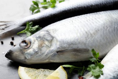 Gri masada tuzlanmış ringa balıkları ve baharatlar, yakın plan.