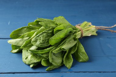 Mavi ahşap masada taze yeşil kuş yaprakları, yakın plan.