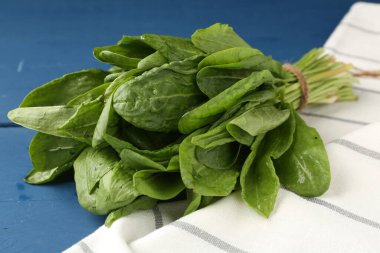 Mavi ahşap masada taze yeşil kuş yaprakları, yakın plan.