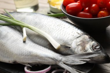Tuzlu ringa balıkları, baharatlar ve domatesler masada, yakın plan.