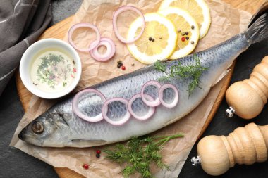 Lezzetli ringa balığı, siyah masada baharatlar, düz uzanmış.