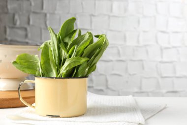 Kase içinde taze kuş yaprakları ve beyaz masada kevgir, metin için boşluk.