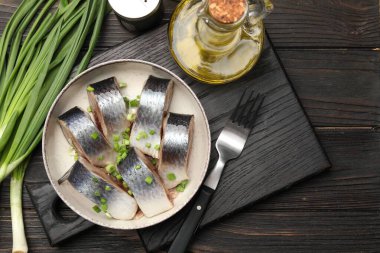 Lezzetli ringa balıkları. Yeşil soğanlı. Siyah ahşap masada servis ediliyor.