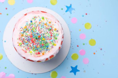 Lezzetli pasta, konfeti ve açık mavi masaya serpiştirilmiş şekerler.