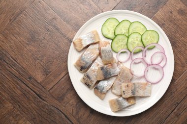 Lezzetli ringa balıkları, soğan ve ahşap masa üzerindeki salatalık dilimleri, üst manzara. Metin için boşluk