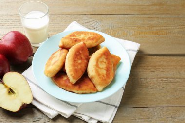 Lezzetli kızarmış pirizky (doldurulmuş turtalar) elma ve sütle ahşap masada.