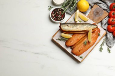 Tütsülenmiş ringa balıkları, baharatlar ve domatesler beyaz mermer masada, düz yerde. Metin için boşluk