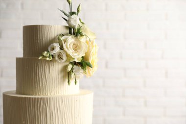 Beyaz arka planda çiçeklerle süslenmiş lezzetli düğün pastası, yakın plan. Metin için boşluk