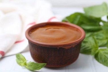 Lezzetli köri sosu ve fesleğen yaprakları beyaz fayanslı masada, yakın plan.