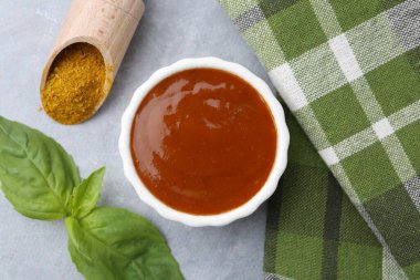 Lezzetli köri sosu, toz ve fesleğen yaprakları gri masada, düz yerde.