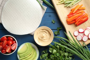 Pirinç kağıt çarşaflar ve mavi ahşap masa üzerindeki farklı malzemeler.