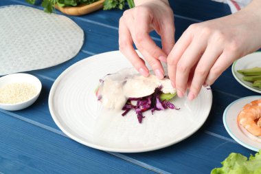 Mavi ahşap masada nefis börek yapan bir kadın, yakın plan.