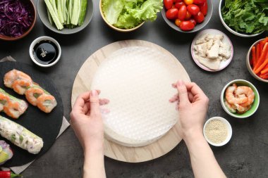 Koyu gri masada nefis börek yapan bir kadın.