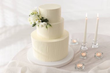 Çiçek desenli nefis düğün pastası ve içeride yanan mumlar.