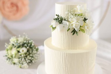 Çiçek desenli nefis bir düğün pastası ve kapalı bir masa, yakın plan.