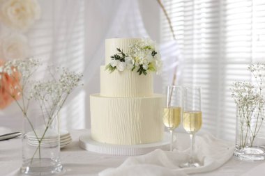 Çiçek desenli nefis düğün pastası ve kapalı bir masada şampanya bardakları.