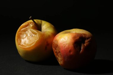 Siyah arka planda iki çürük elma, yakın plan.