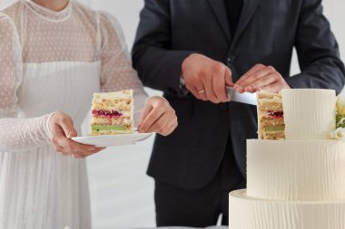 Yeni evliler arka planda düğün pastası kesiyorlar, yakın plan.