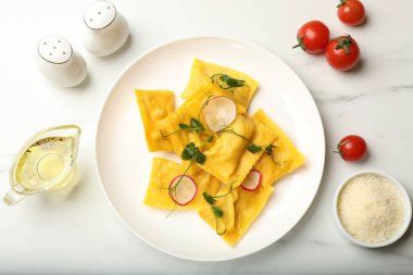 Mikro yeşillikli ravioli, turp ve diğer ürünler ışık masasında, düz yerde.