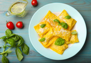 Açık mavi ahşap masada servis edilen peynirli ve fesleğenli nefis ravioli.