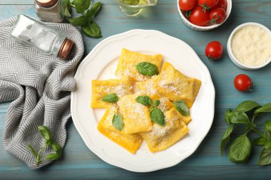 Açık mavi ahşap masada servis edilen peynirli ve fesleğenli nefis ravioli.