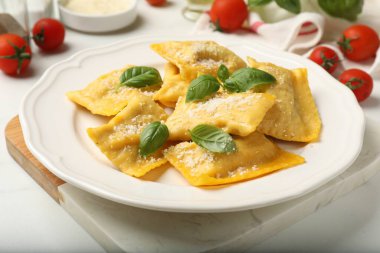 Beyaz masada servis edilen peynirli ve fesleğenli lezzetli ravioli.