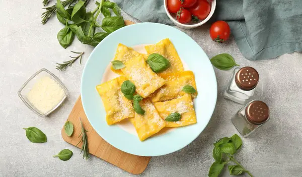 Peynirli ve fesleğenli lezzetli ravioli gri masada servis edilir.