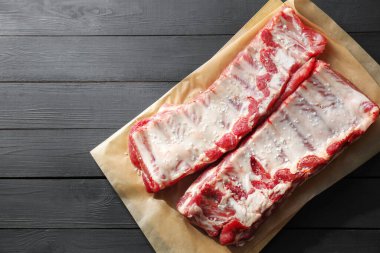 Siyah ahşap masada deniz tuzu ve çiğ domuz pirzolası. Metin için boşluk