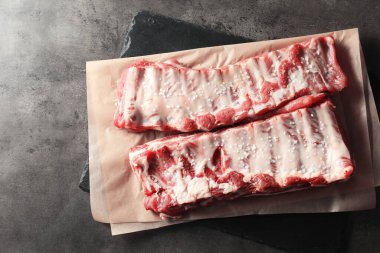 Çiğ domuz kaburgası, deniz tuzu ve gri masa, üst manzara.