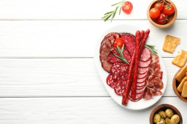 Beyaz ahşap masada servis edilen farklı tütsülenmiş sosisler. Metin için boşluk