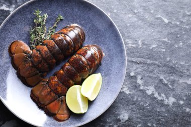 Çiğ ıstakoz kuyruğu, kireç ve kekik karanlık masa, üst manzara. Metin için boşluk