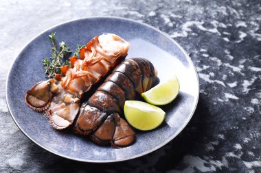 Çiğ ıstakoz kuyruğu, kireç ve kekik karanlık masada, yakın plan. Metin için boşluk