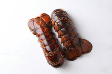 Çiğ ıstakoz kuyrukları beyaz masada, düz yerde.