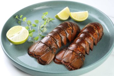 Çiğ ıstakoz kuyruğu, kireç ve mikro yeşiller beyaz masada, yakın plan.