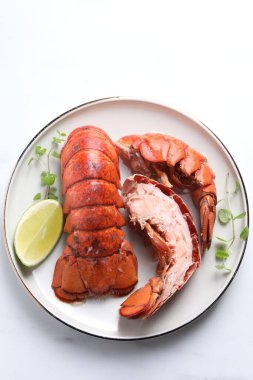 Beyaz masada servis edilen lezzetli haşlanmış ıstakoz kuyrukları.