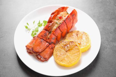 Lezzetli ıstakoz kuyruğu, mikro yeşillikler ve limon dilimleri gri desenli masa, yakın plan.