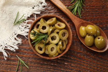 Lezzetli marine edilmiş zeytin halkaları kasede, kaşık dolusu ve ahşap masada biberiye, düz uzanmış.