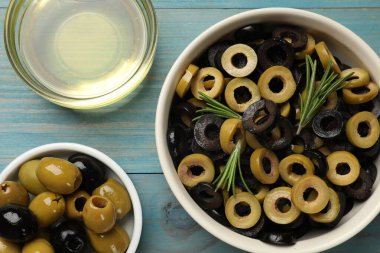 Farklı lezzetli marine edilmiş zeytin halkaları, bütün olanlar, biberiye ve yağ açık mavi ahşap masa, düz uzanmış
