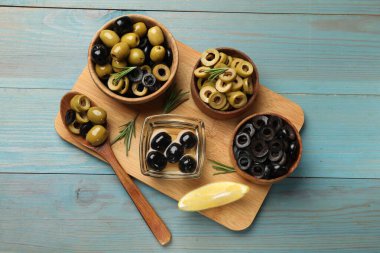 Farklı lezzetlerde marine edilmiş zeytin halkaları, tüm olanlar ve biberiye açık mavi ahşap masa, düz yatıyordu.