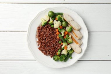 Lezzetli kahverengi pirinç, sebzeli ve tavuklu beyaz ahşap masa, üst manzara