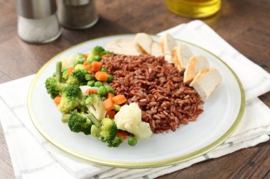 Tahta masada servis edilen tavuk ve sebzeli lezzetli kahverengi pirinç.