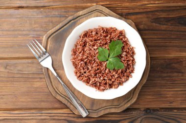 Ahşap masada servis edilen maydanozlu lezzetli kahverengi pirinç.