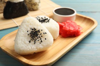 Pirinç topları (onigiri), soya sosu ve açık mavi ahşap masa üzerinde turşulu zencefil, yakın plan. Geleneksel Japon yemeği